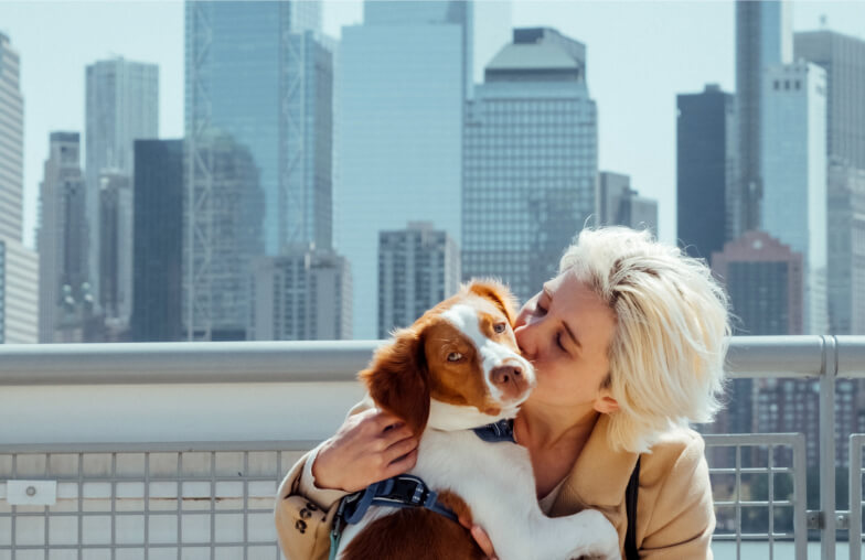 Woman kissing dog by skyline