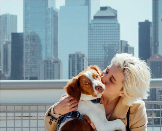 Woman kissing dog by skyline